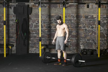 Ağır bir halter salonunda ile eğitim genç sakallı ve gömleksiz atlet. Kopyalama alanı alanı konseptiyle karanlık fotoğraf.