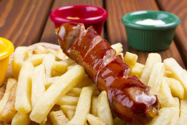 Izgara domuz eti frankfurter sosis kızartması, cips ve sos sos ile.