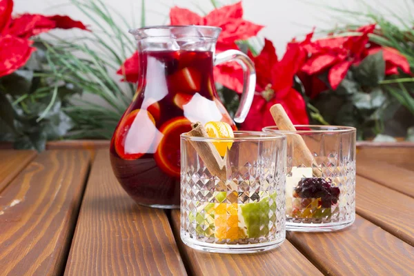 Red wine sangria or punch with fruits and ice in glasses and pincher. Homemade refreshing fruit sangria over rustic wooden table, copy space.