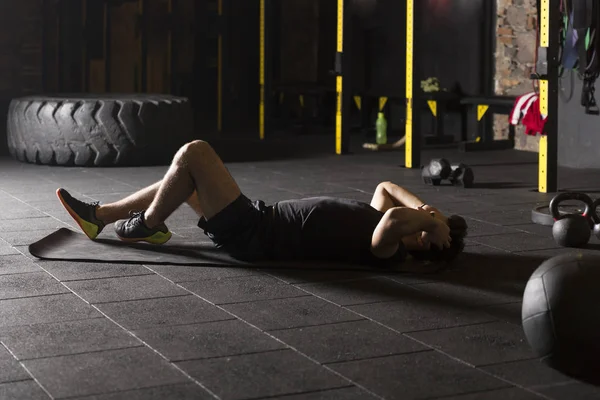 在健身房练习黑色仰卧起坐的年轻运动员 — 图库照片