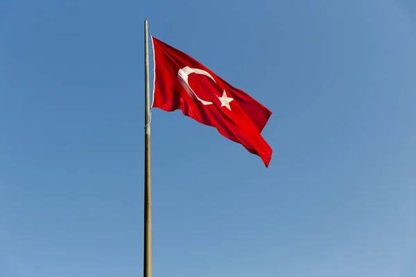 青い空に手を振っている長い金属の鉄の棒にトルコ国旗 赤い旗は白い星と三日月を搭載します フラグ バイラクが呼ばれ トルコの国歌に Sancak と呼ばれます — ストック写真
