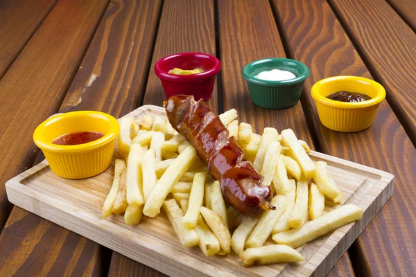 Grilled pork frankfurter sausage with french fries, chips and dip sauces.