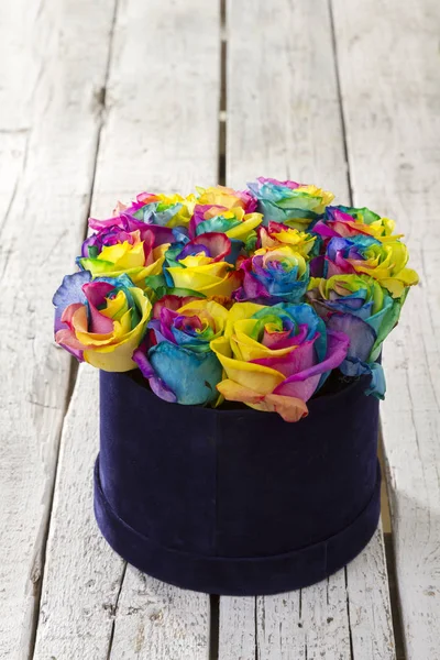 close up view of painted colorful bouquet of roses in box on wooden background