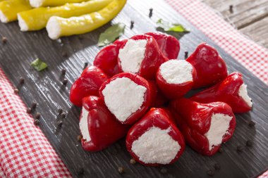 Yumuşak peynir Beyaz ahşap rustik arka plana sahip siyah koyu plaka üzerinde meze meze tatlı kiraz kırmızı ve yeşil kiraz biber dolması. 