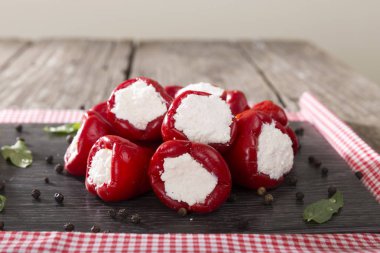 Yumuşak peynir Beyaz ahşap rustik arka plana sahip siyah koyu plaka üzerinde meze meze tatlı kiraz biber dolması.