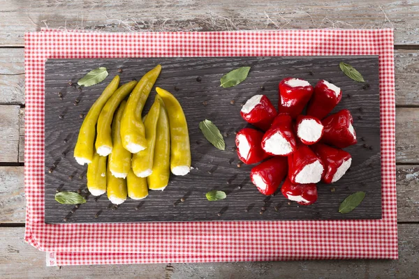 Yumuşak peynir Beyaz ahşap rustik arka plana sahip siyah koyu plaka üzerinde meze meze tatlı kiraz kırmızı ve yeşil kiraz biber dolması. 