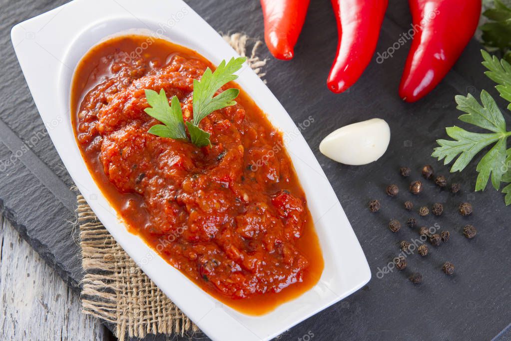 Turkish and Arabian traditional appetizer Closeup of hot red pepper paste in plate on rustic white wooden table. Copy space for text area.