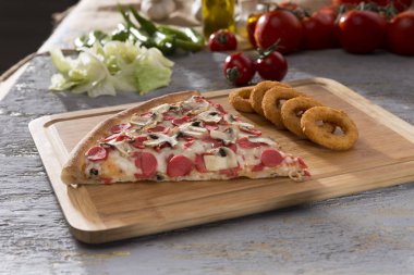 İtalyan pizza ve kızarmış soğan halkaları ahşap kesme tahtası üzerinde hizmet parça görünümünü kapat