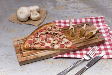 gri zemin üzerine ahşap kesme tahtası üzerinde parça İtalyan pizza ve baharat görünümü kadar kapatın