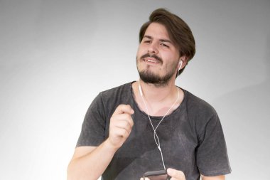 adam akıllı telefon dinleme müzik gri arka plan üzerinde kulaklık