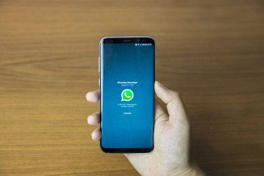 Izmir, Türkiye - 27 Haziran 2017: kısmi smartphone ahşap zemin üzerinde tutan adam görünümünü