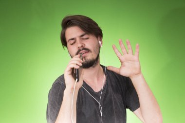 adam akıllı telefon dinleme müzik yeşil arka plan üzerinde kulaklık