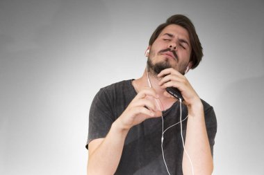 adam akıllı telefon dinleme müzik gri arka plan üzerinde kulaklık