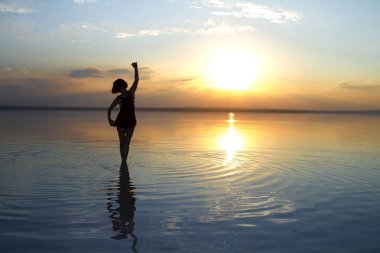 güzel gün batımı sırasında denizde dans eden kadın