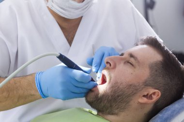 diş kliniğinde diş hekimi ve erkek hastanın kısmi görünümü