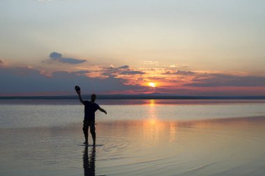 gün batımı sırasında sahil topu ile oynayan adam