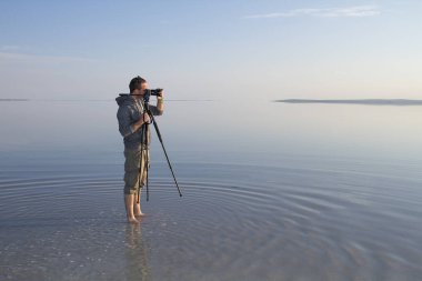 deniz kıyısında fotoğraf makinesi ile genç fotoğrafçı