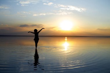 güzel gün batımı sırasında denizde dans eden kadın