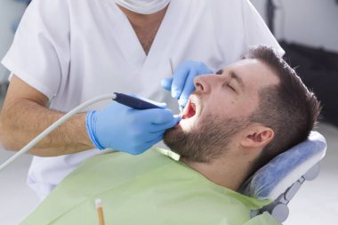 diş kliniğinde diş hekimi ve erkek hastanın kısmi görünümü
