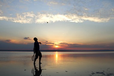 gün batımı sırasında sahilde yalnız tenis oynayan adam