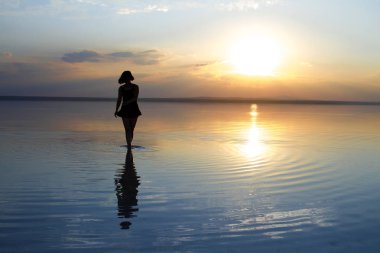 güzel gün batımı sırasında denizde dans eden kadın
