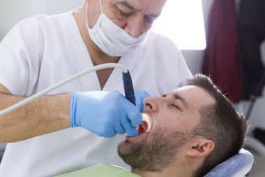 Diş Hekimliği kliniğinde prosedür sırasında dişçi ve erkek hasta
