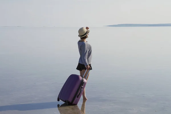 young woman with luggage walking at seashore