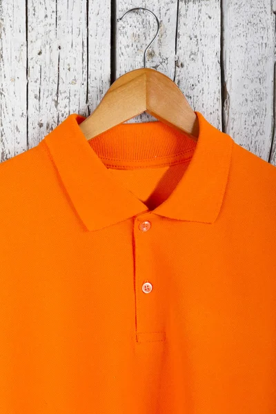 close up view of stylish orange shirt on hanger on wooden wall background