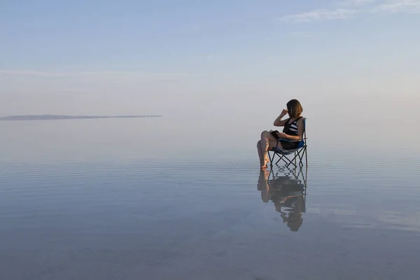 young woman with book resting in chair at seashore