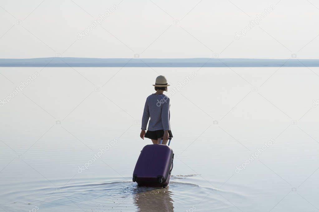 back view of woman with baggage walking in sea