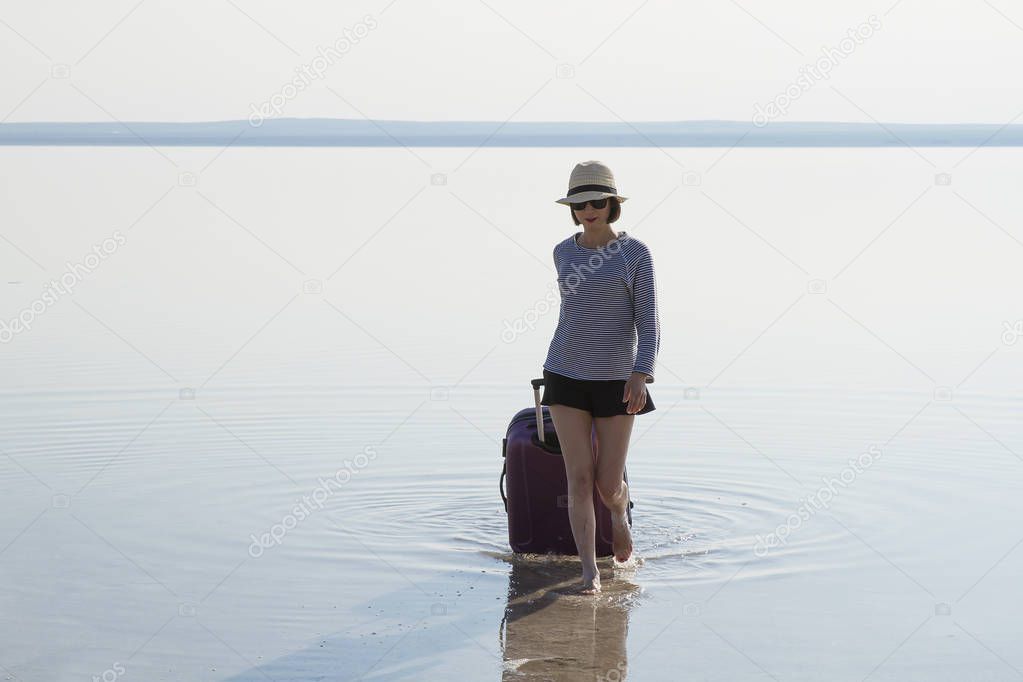 young woman with luggage walking at seashore