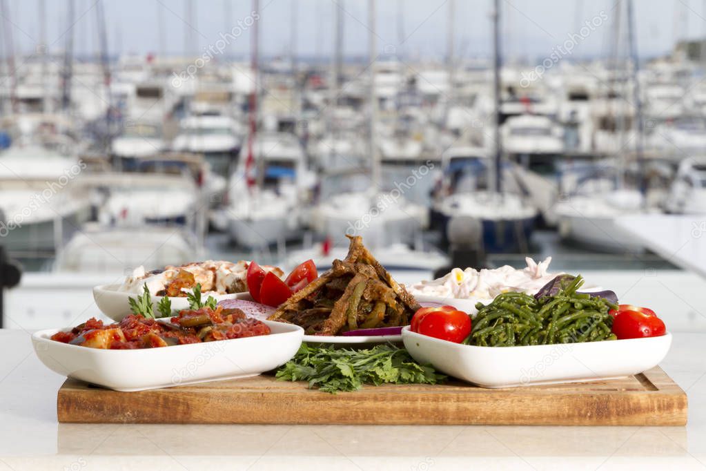 close up view of table served with different dishes with ships on backdrop