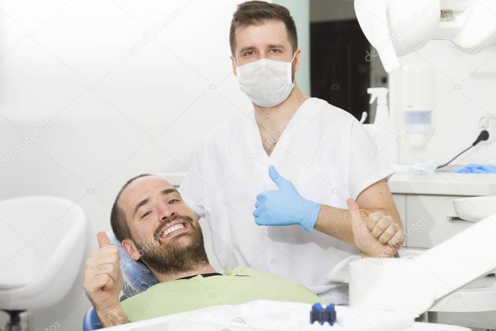 young dentist and happy patient at dental clinic