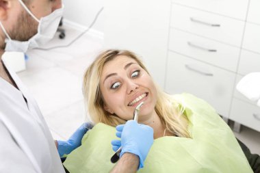 diş kliniğinde prosedür sırasında erkek dişçi ve genç kadın hasta