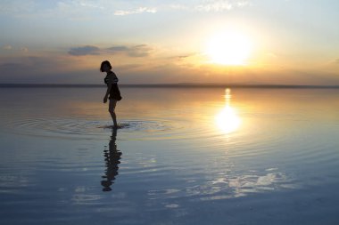 güzel gün batımı sırasında denizde dans eden kadın