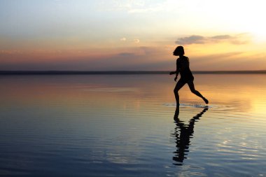 güzel gün batımı sırasında denizde dans eden kadın