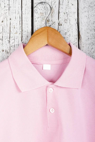 close up view of stylish pink shirt on hanger on wooden wall background