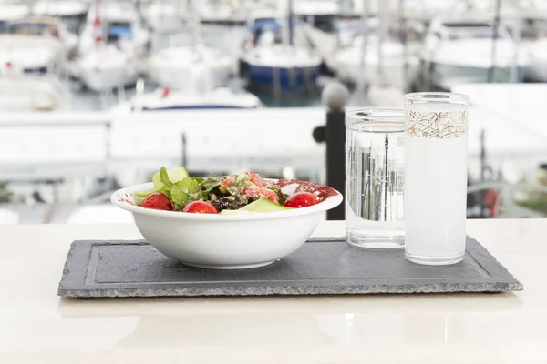 close up view of served salad and drinks on table with ships on background