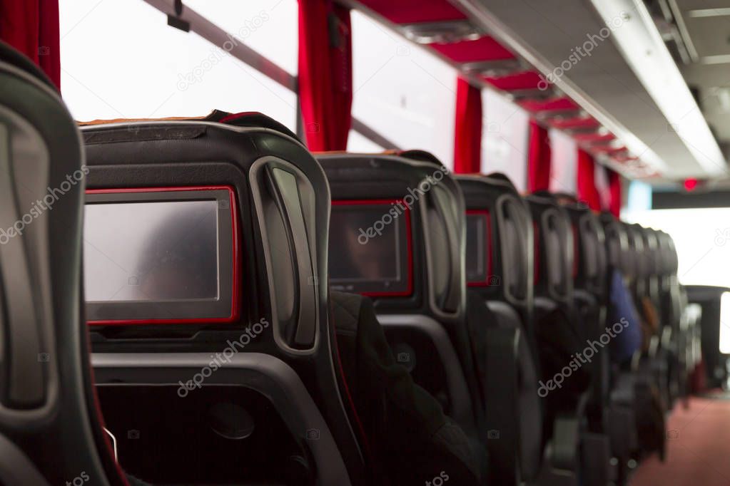 close up view of empty leather seats with blank screens in bus
