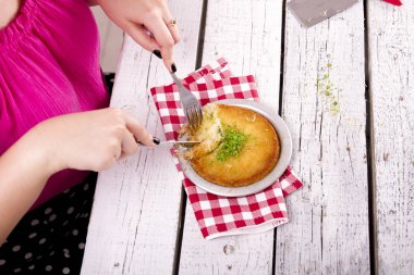 ahşap masada peynir yemeği yiyen kadının kısmi görünümü
