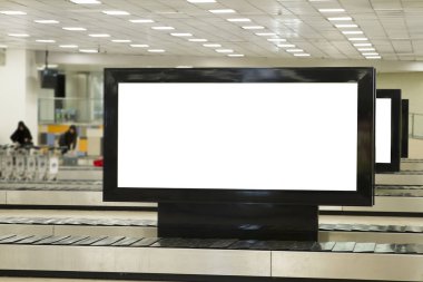 Havaalanında büyük yatay boş beyaz Billboard ekran. İnsanlar bagajları bekliyor ve arka planda konuşuyor. Seçici odak.