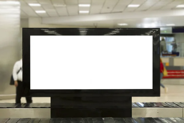 Big Horizontal Blank White Billboard Screen in airport. People are waiting luggage and talking at background. Selective Focus.