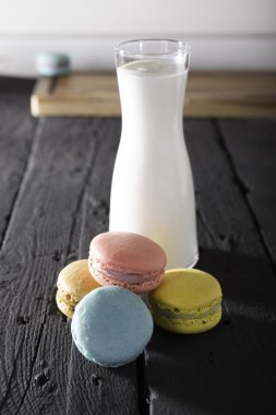 ahşap masa üzerinde cam sürahi tatlı renkli macaroons kurabiye ve süt yakın çekim görünümü