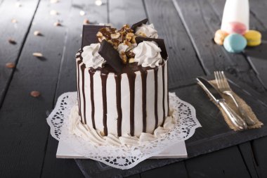 Tahta masadaki tatlı gurme şenlik pastasının yakın görüntüsü. Beyaz kremalı pasta, erimiş çikolatalı, koyu renkli ahşap masa arkaplanı..