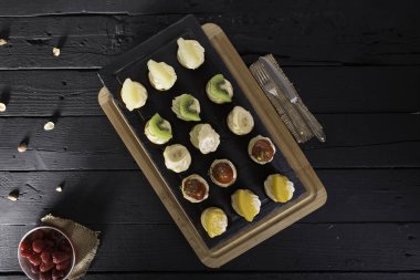 Tahta masadaki meyveli tatlı gurme tatlılarının en üst görüntüsü. Taze çilekli tartlar, ananas, mango, kivi, portakal ve muz ahşap masa arkasında..