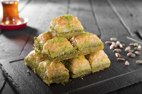 Ahşap masada fındıklı ev yapımı lezzetli fırının yakın plan görüntüsü. Türk ramazanı Baklava şam fıstığı ve siyah Arap çayı