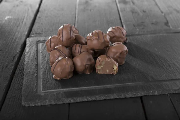 Vista Cerca Deliciosos Caramelos Chocolate Pizarra Negra Sobre Mesa Madera —  Fotos de Stock