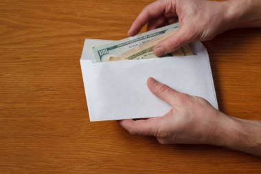 Aç gözlü tüylü adamın elleri devraldı bazı rüşvet bizi dolar banknotlar boş beyaz zarfın içinde ahşap bir meşe masa ofis