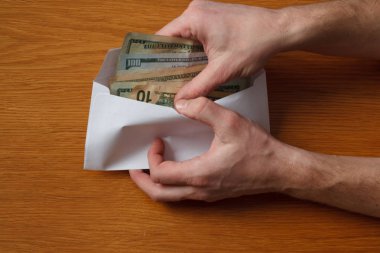 Aç gözlü tüylü adamın elleri devraldı bazı rüşvet bizi dolar banknotlar boş beyaz zarfın içinde ahşap bir meşe masa ofis