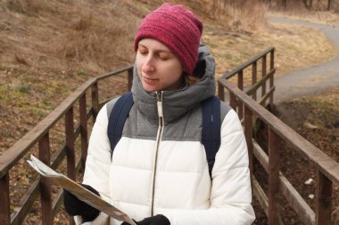 Yetişkin genç kadın sıcak sacual giysili seyahat ve Milli Park arka plan üzerinde bir yere nasıl harita üzerinde bir yol arıyorum